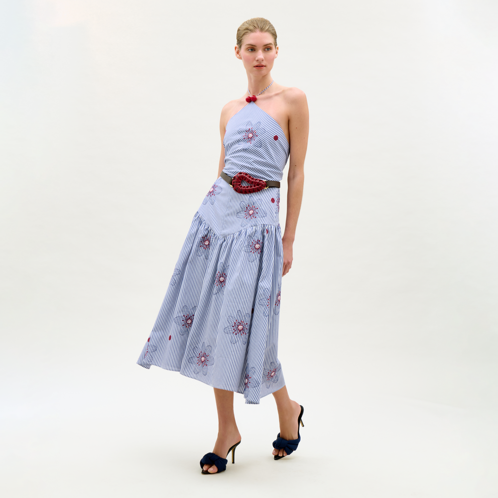 Woman wearing a blue floral dress with a red belt on a white background