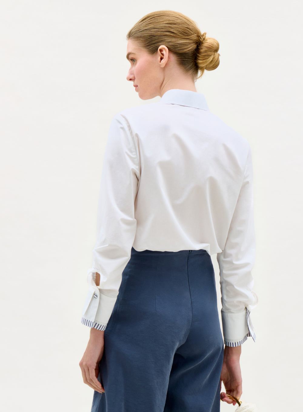 Woman wearing a white shirt and blue pants on a plain background