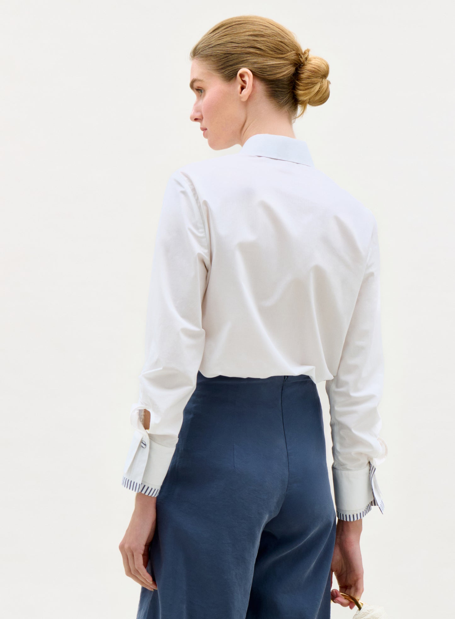 Woman wearing a white shirt and blue pants on a plain background
