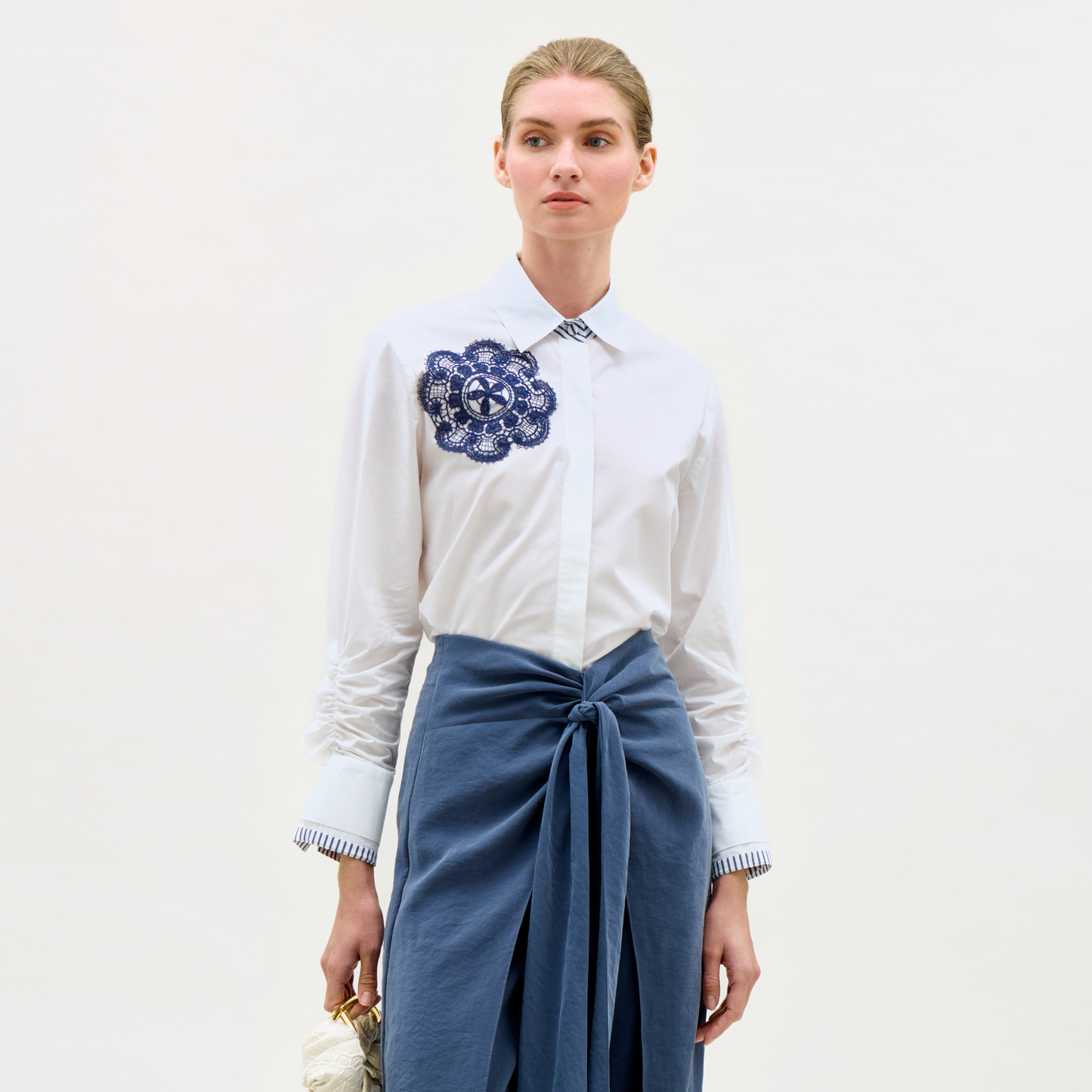 Woman wearing a white shirt with a blue floral design and a blue skirt on a white background