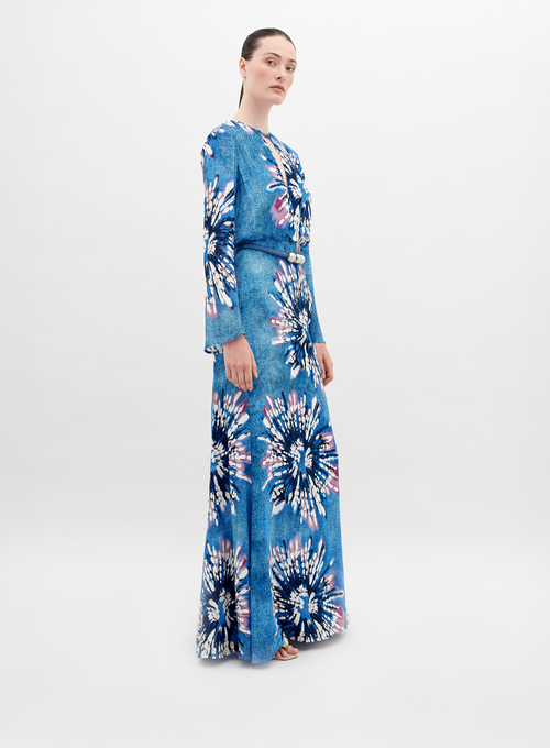 A person stands wearing the Ravenna Dress Aciano Flower, looking off to the side against a plain white background. Pre-order now to ensure it arrives by November 15th, 2024.