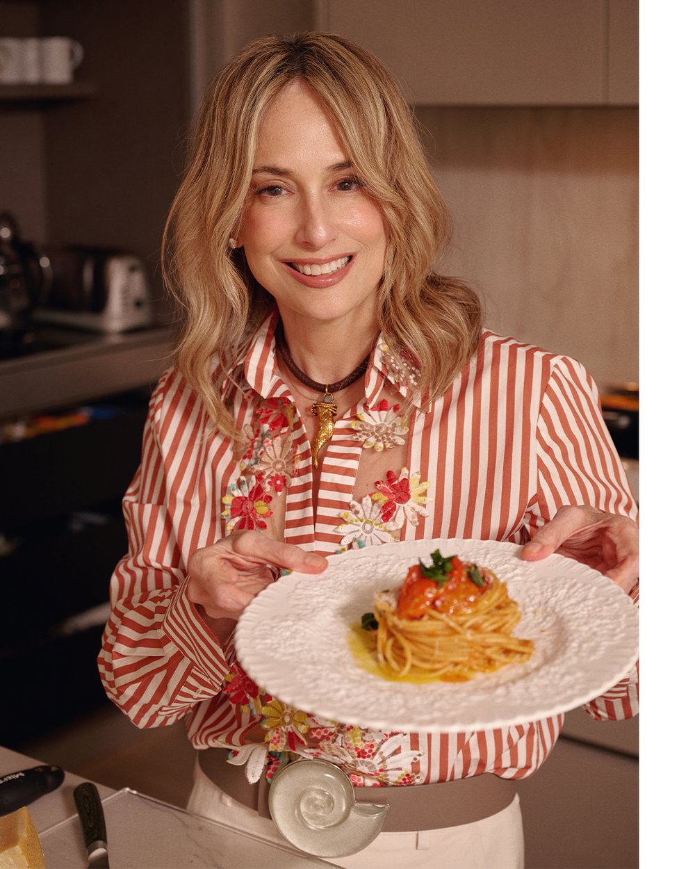 Woman holding a plate of spaghetti in a kitchen