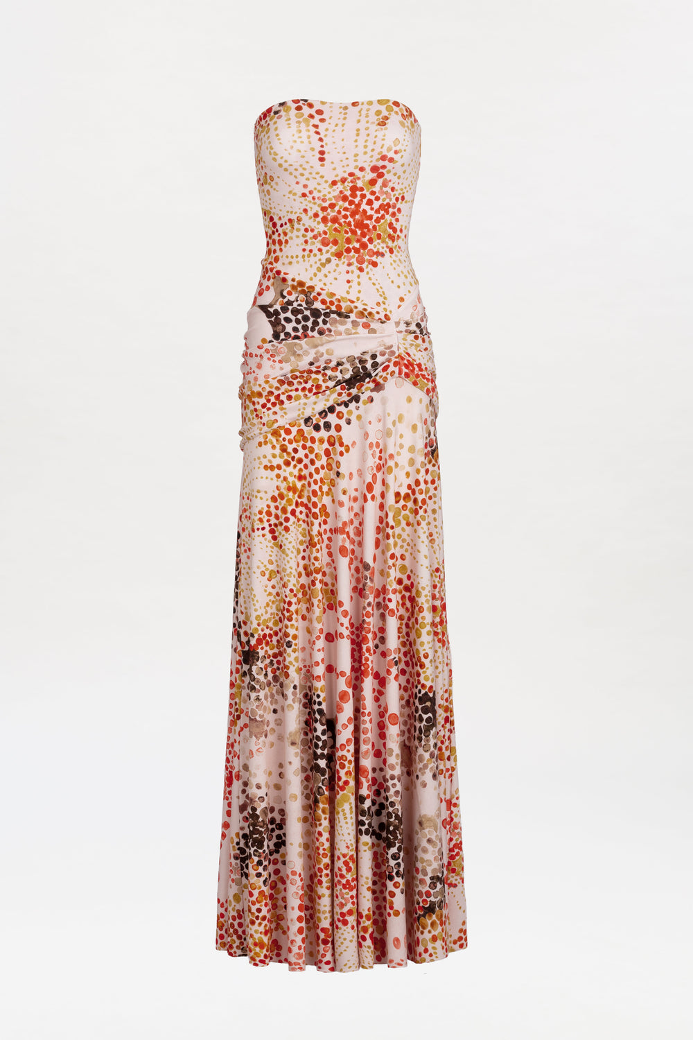 The Shani Dress is a strapless, floor-length gown featuring a fitted bodice and a vibrant polka dot pattern in red, orange, brown, and pink hues on a light background.