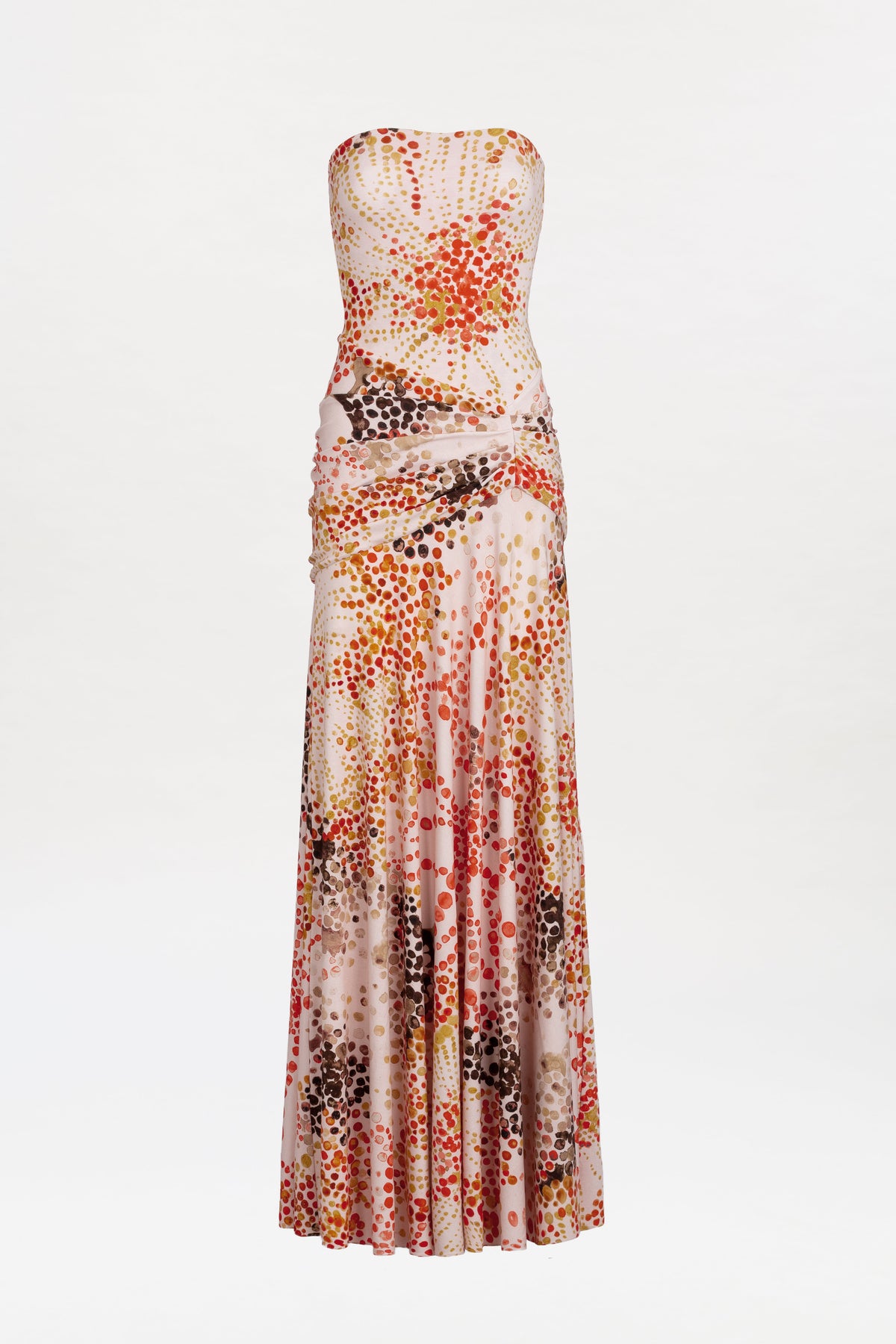 The Shani Dress is a strapless, floor-length gown featuring a fitted bodice and a vibrant polka dot pattern in red, orange, brown, and pink hues on a light background.