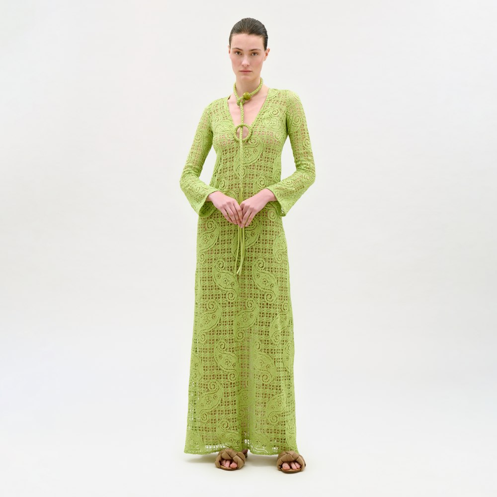 Woman wearing a green lace dress and cardigan on a white background