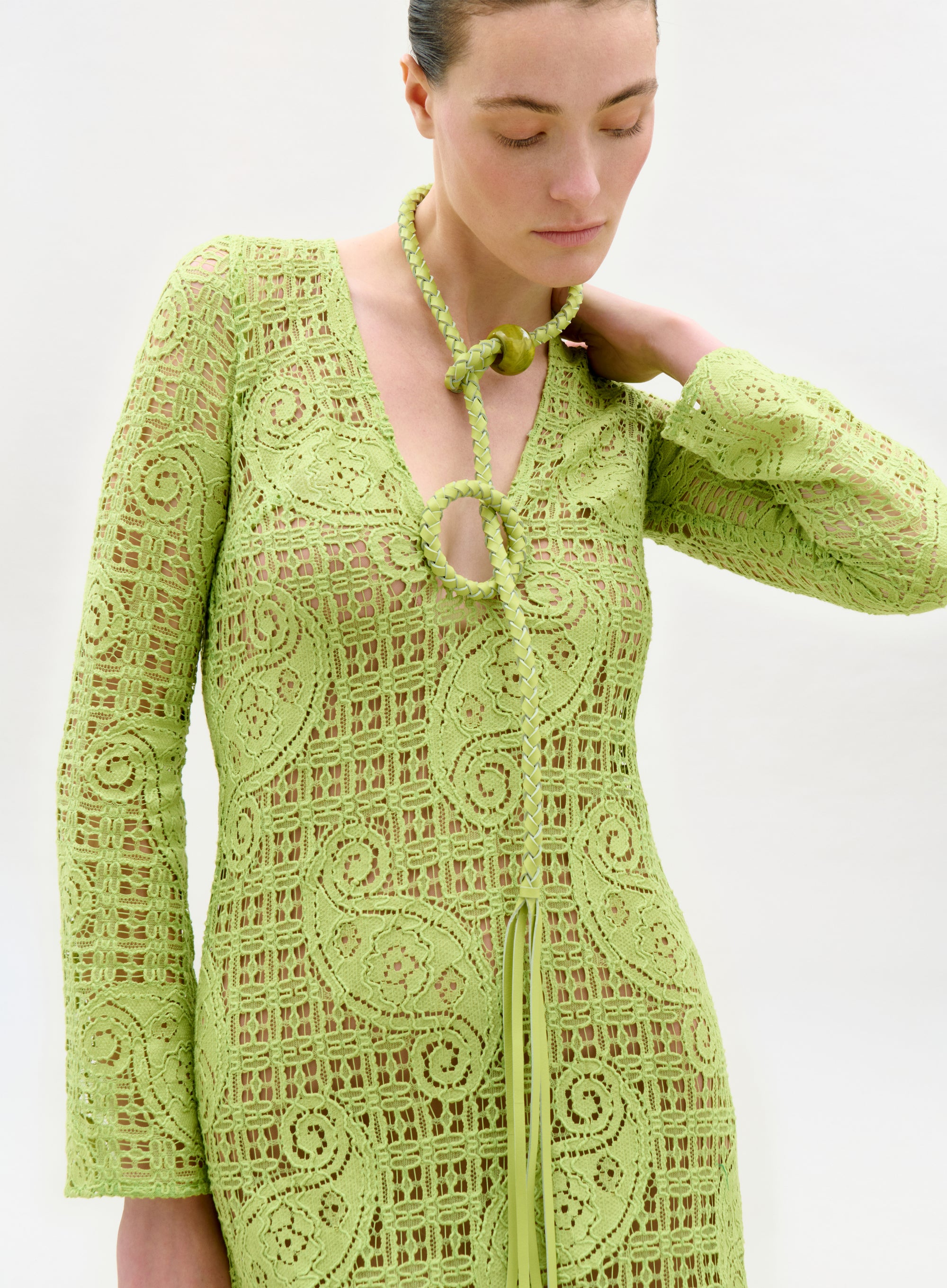 Woman wearing a green lace dress against a white background