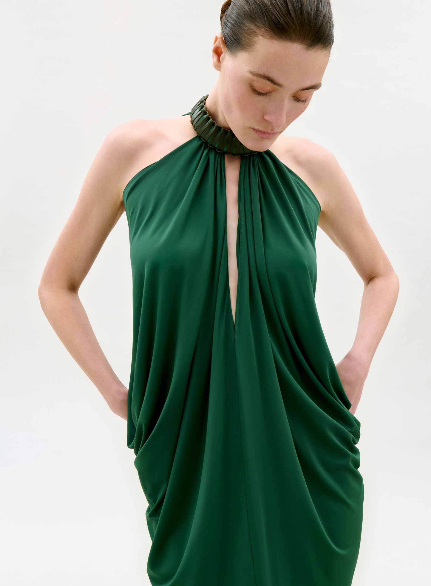 Woman wearing a green halter neck dress against a white background