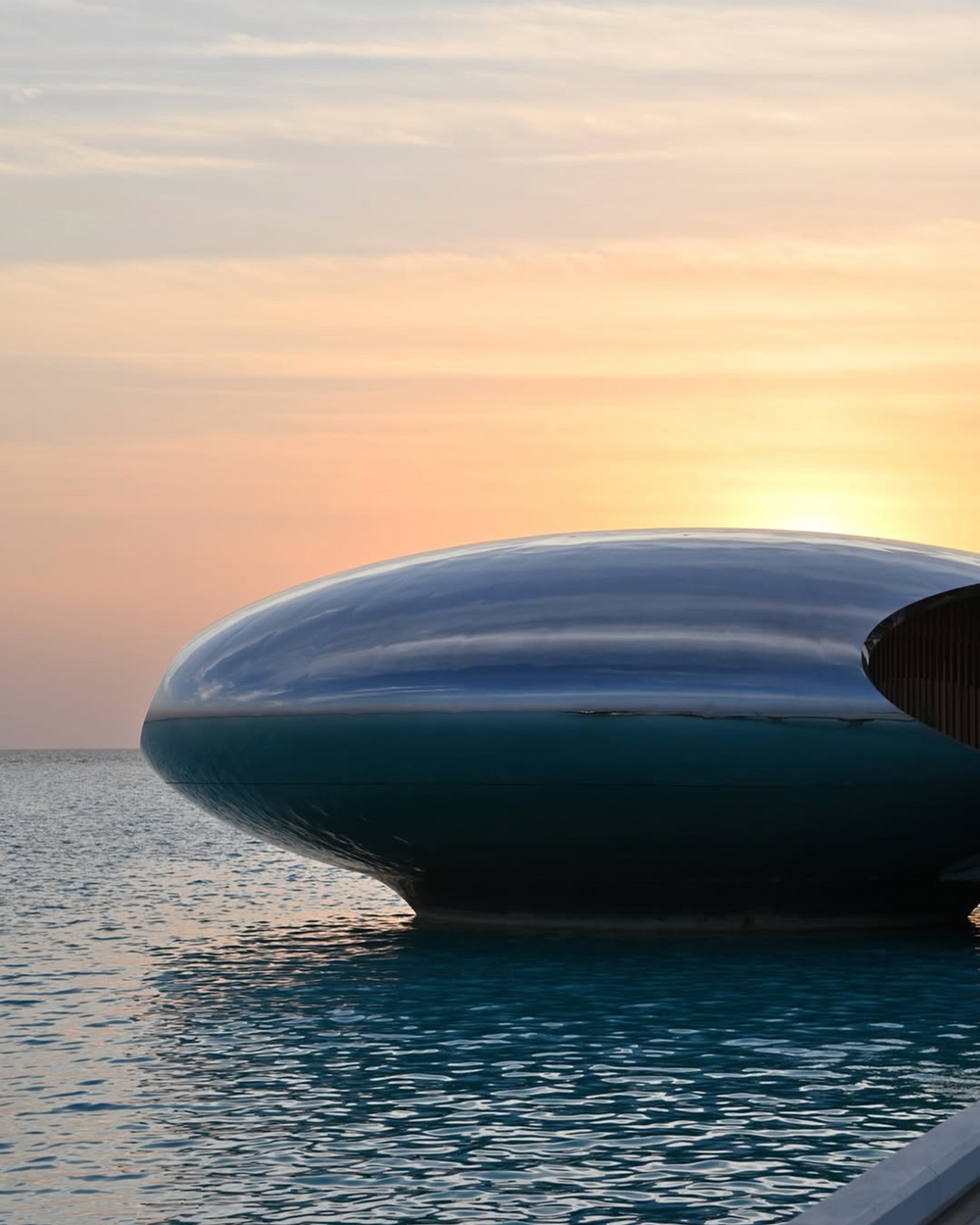 Modern building with a unique design on water at sunset