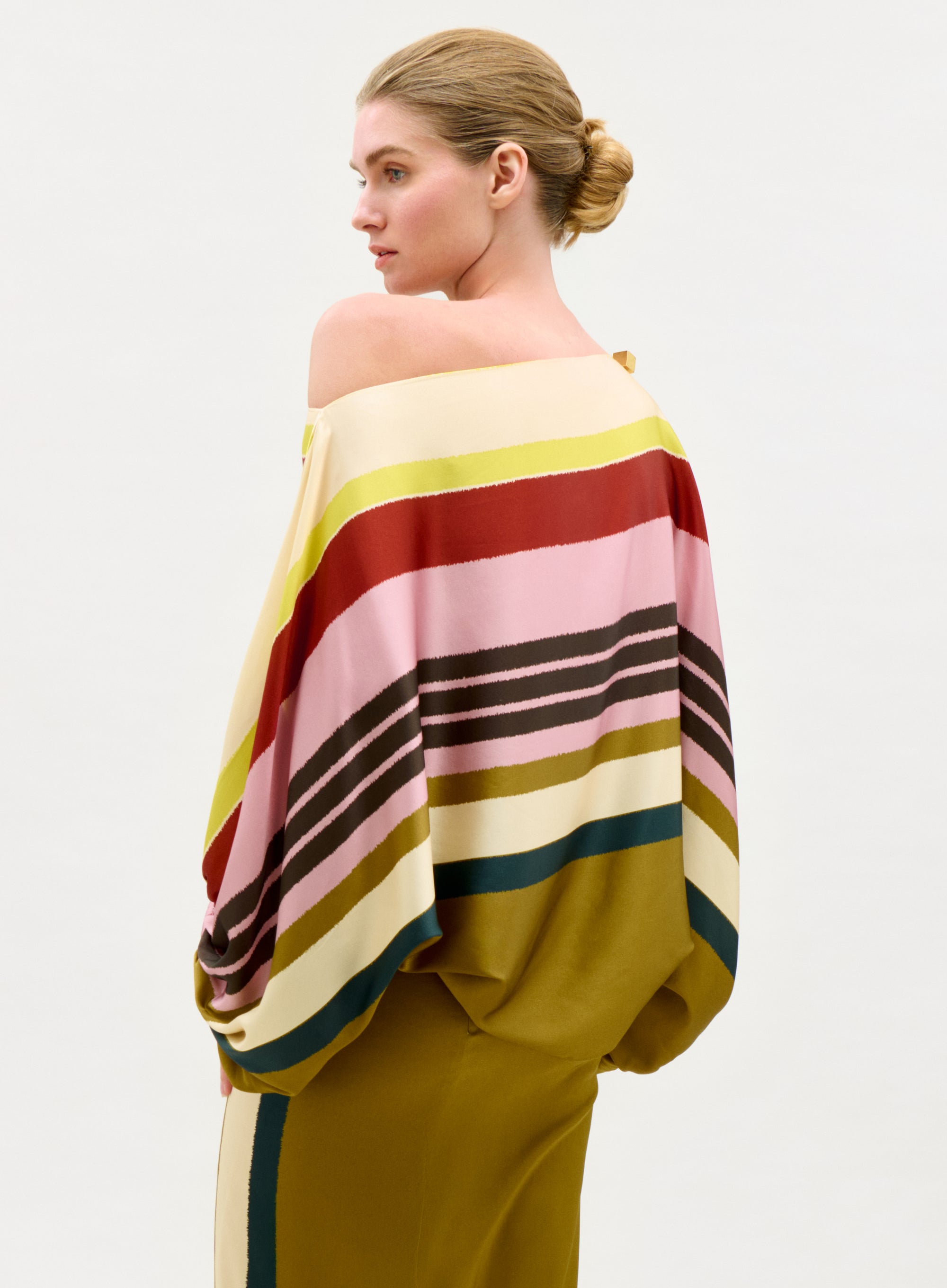 Woman wearing a colorful striped poncho against a plain background