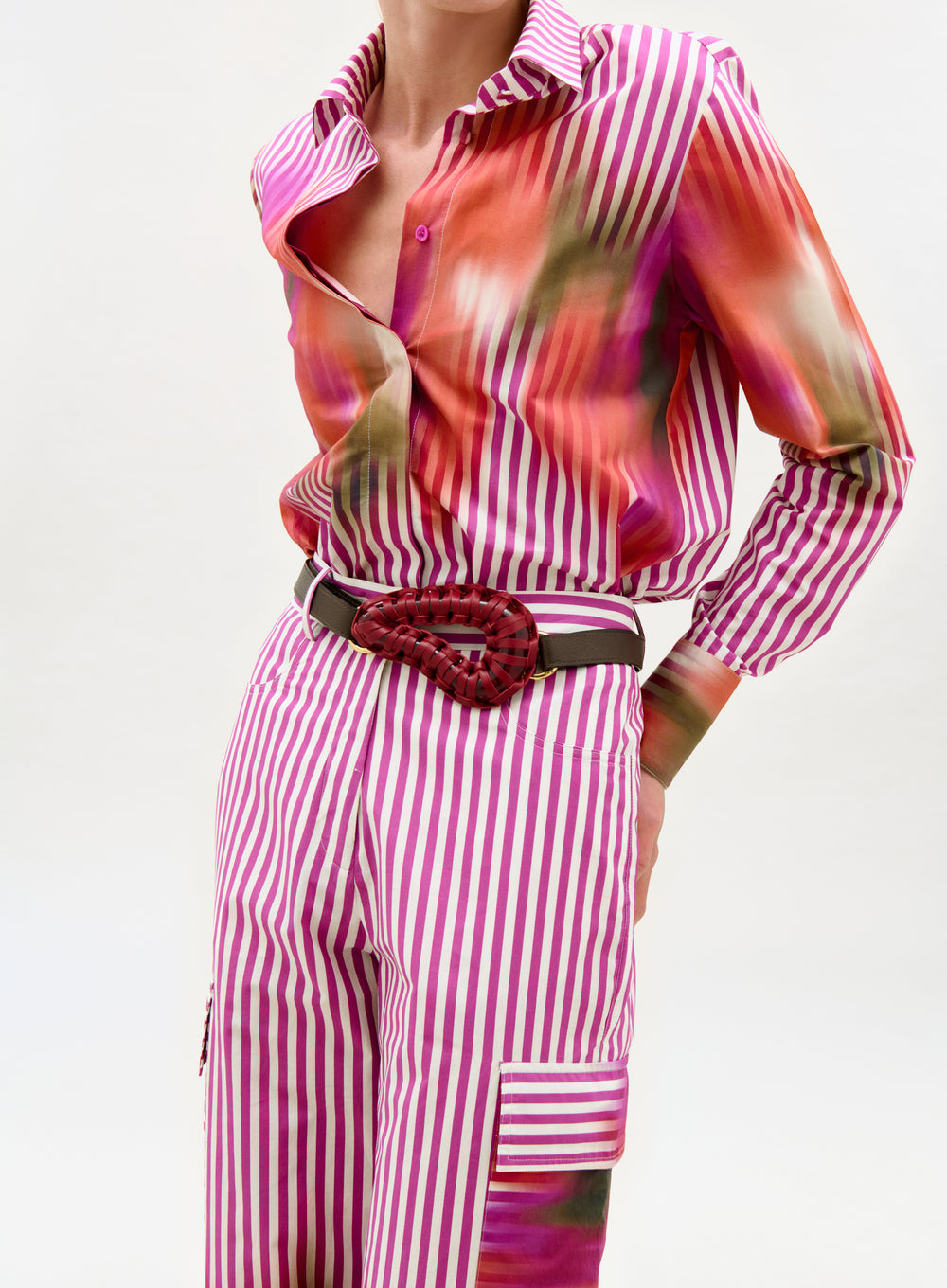 Person wearing a pink and white striped outfit with a belt on a white background
