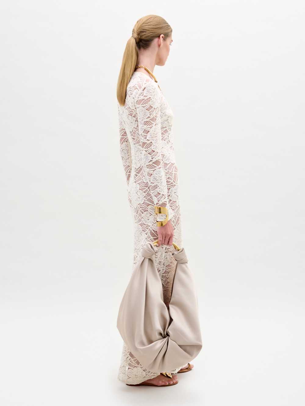 Woman wearing a white lace dress with beige pants on a white background