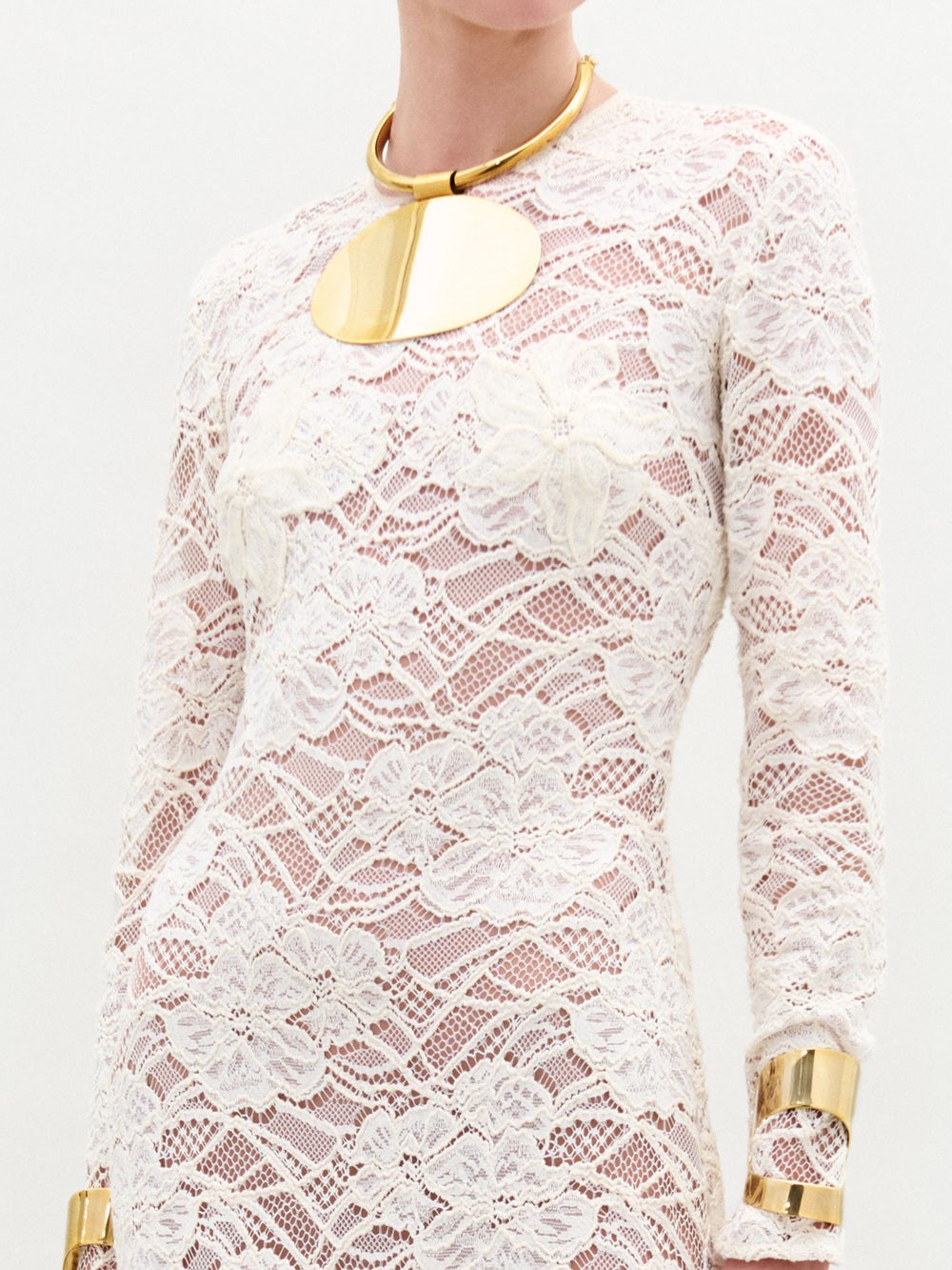 White lace dress with gold accents on a plain background