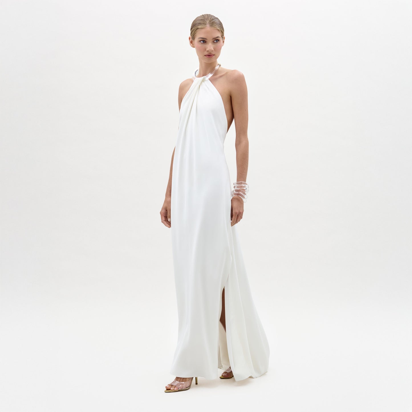 Woman wearing a white halter neck gown on a plain background