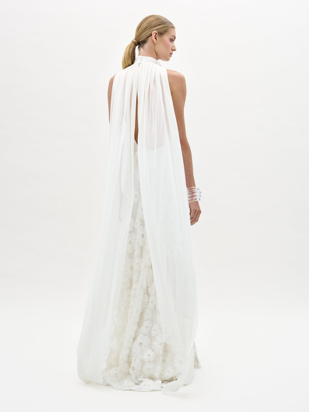 Woman wearing a long, flowing white dress on a plain background