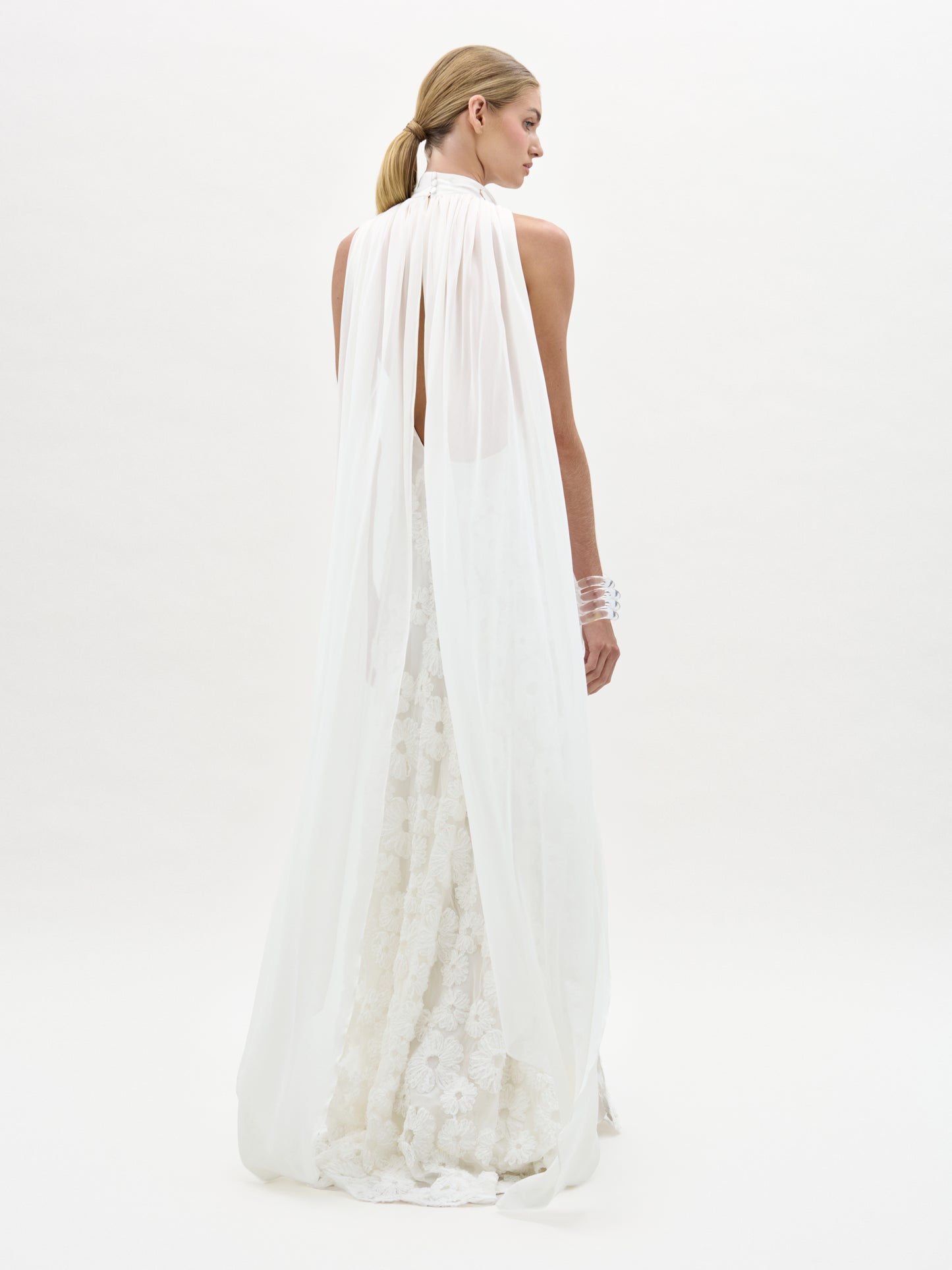 Woman wearing a long, flowing white dress on a plain background