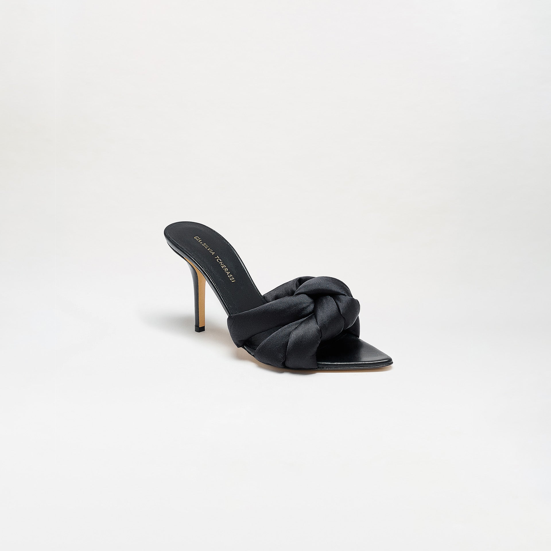 The Ana Heels are single black high-heeled mule sandals featuring a satin braided strap, open toe, thin stiletto heel, and expertly crafted from Italian leather, displayed on a plain white background.