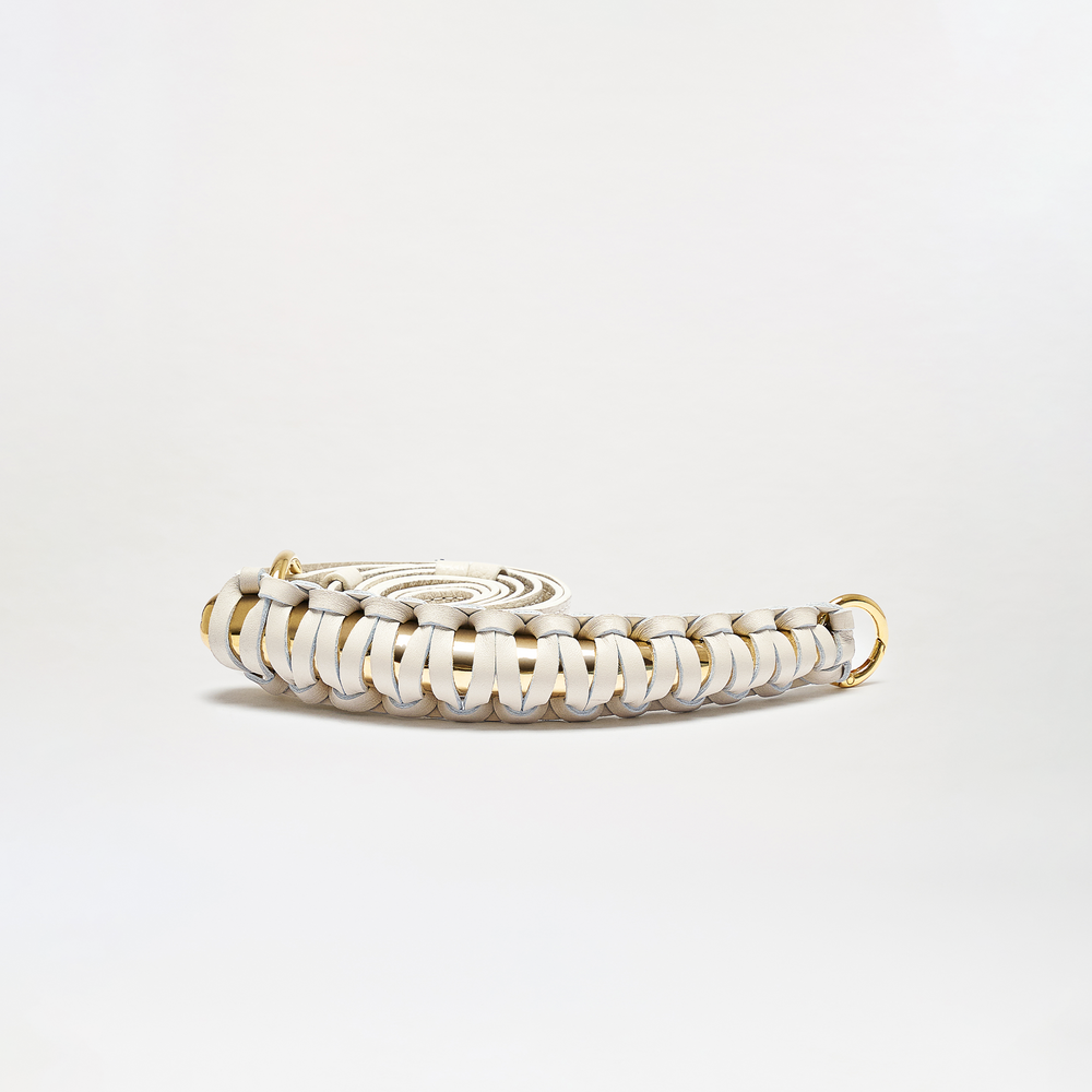 The Ife Belt is a coiled, woven white leather accessory featuring gold-tone metal rings at both ends, shown against a plain white background.