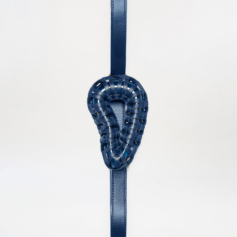 The Renata Belt is a blue leather strap featuring a woven, ear-shaped blue leather centerpiece, shown vertically against a plain white background.