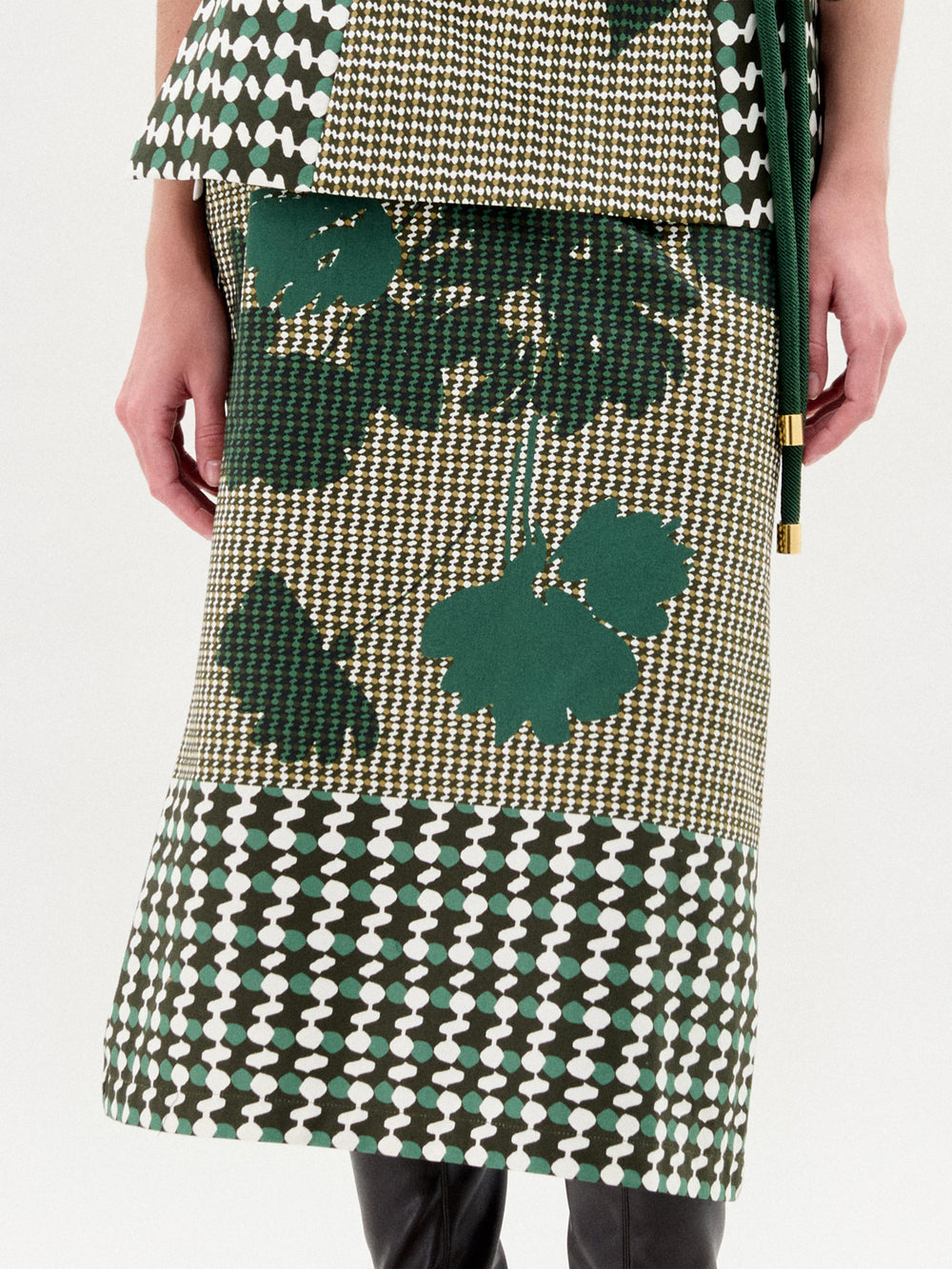 Woman wearing a green skirt with black knee-high boots on a white background