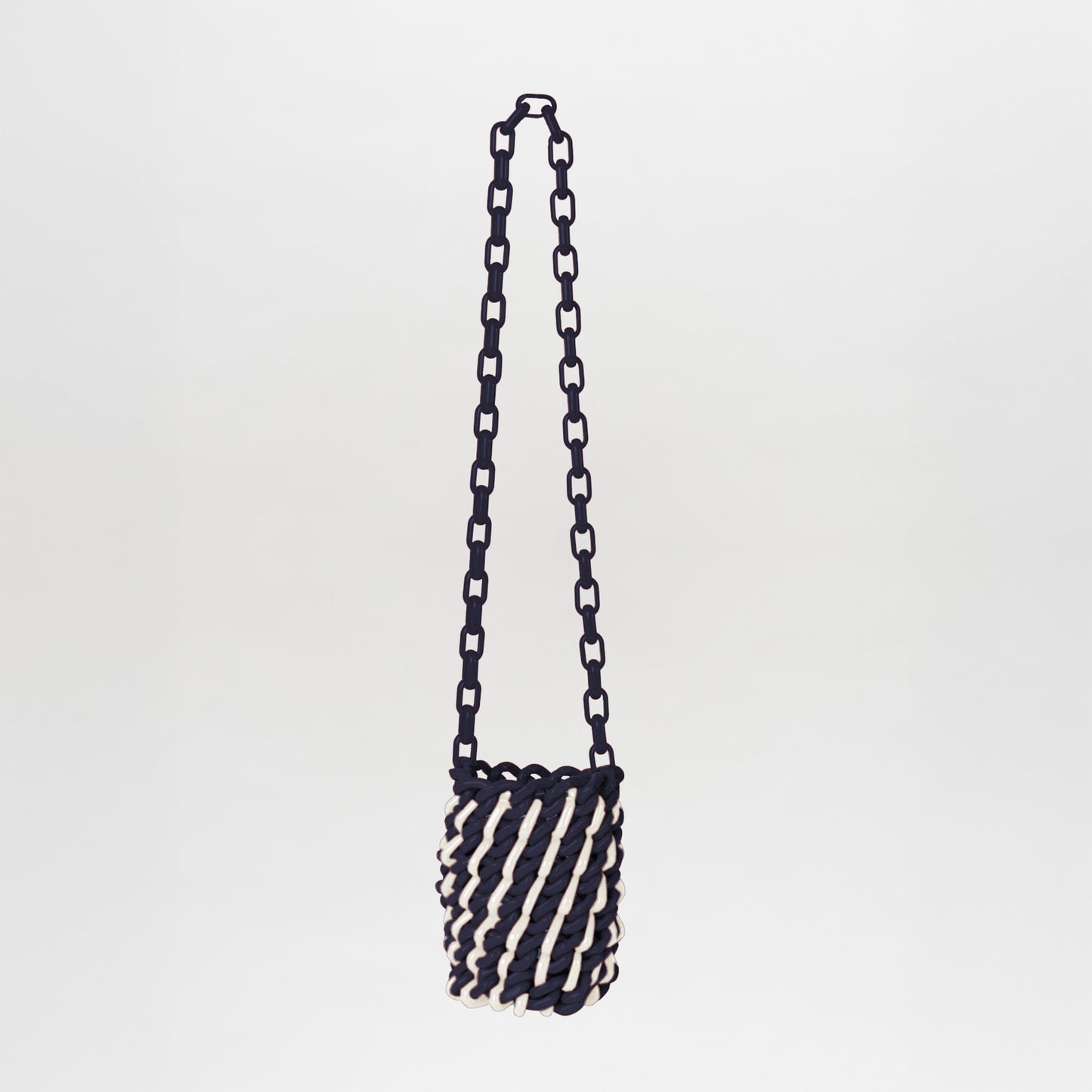 The Anise Bag Navy White is a small cylindrical bag with a chunky chain strap, twisted navy-and-white rope design, and unique resin rings, set against a plain background.