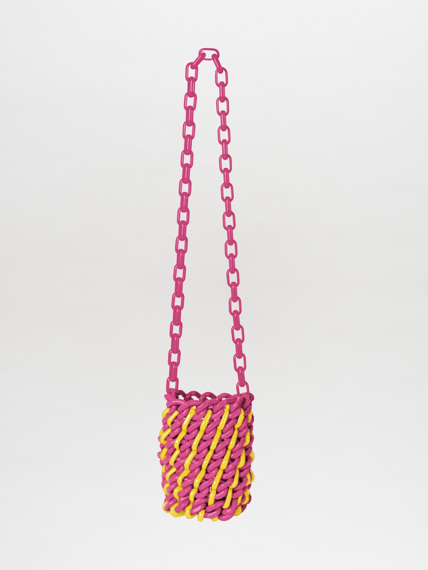 The Anise Bag Fuchsia Yellow showcases interlinked resin shapes, complemented by a pink chain strap and a woven basket-like body in vibrant fuchsia and yellow on a plain white background.