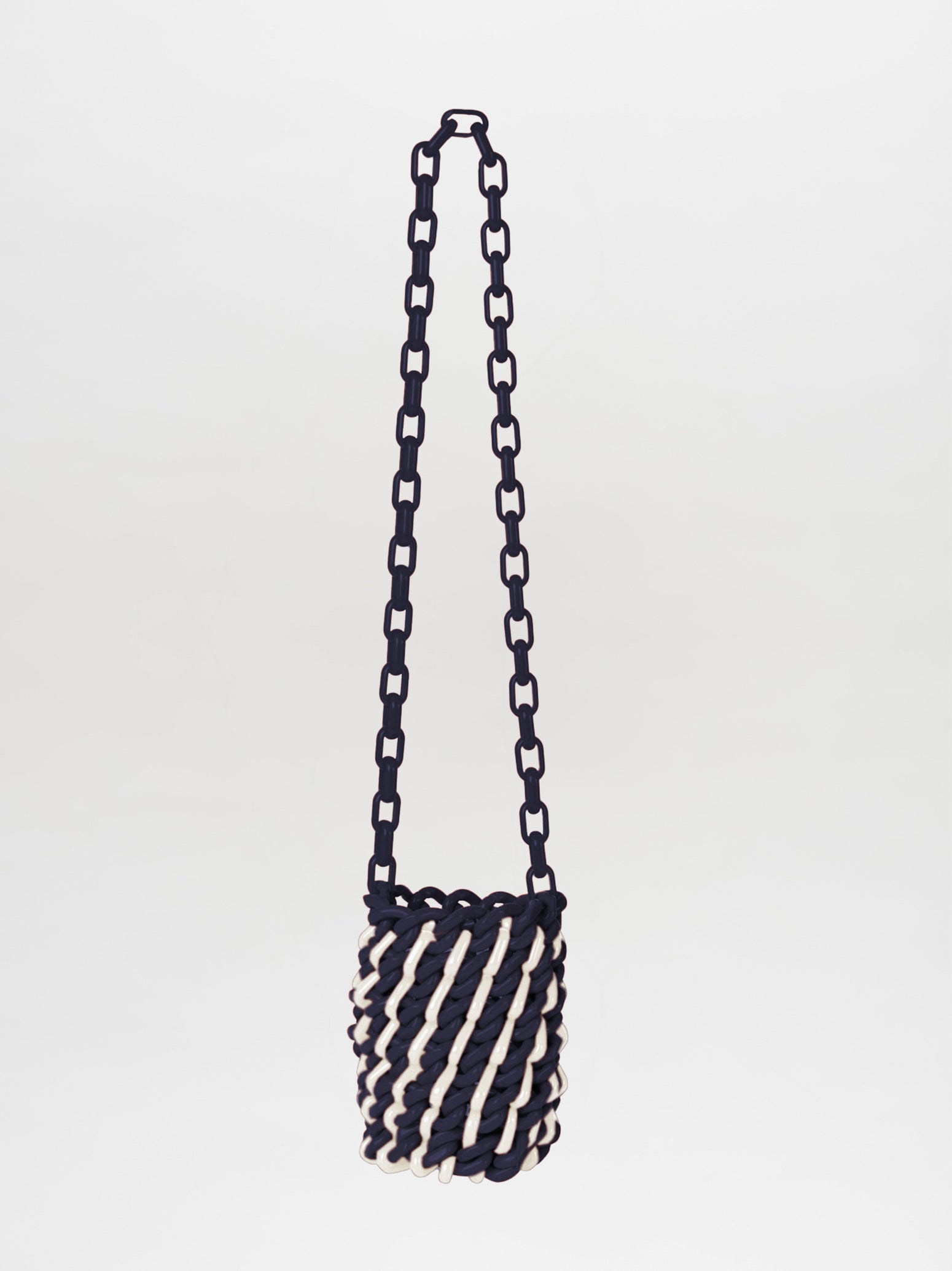 The Anise Bag Navy White is a woven handbag with a chain strap, featuring a navy and white spiral design.