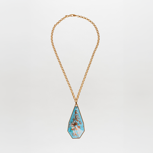 The Ascoli Necklace by Tcherassi showcases a gold chain with a large teardrop-shaped turquoise fantasy stone pendant, accentuated by brown veining and set in an elegant metallic frame against a white background.