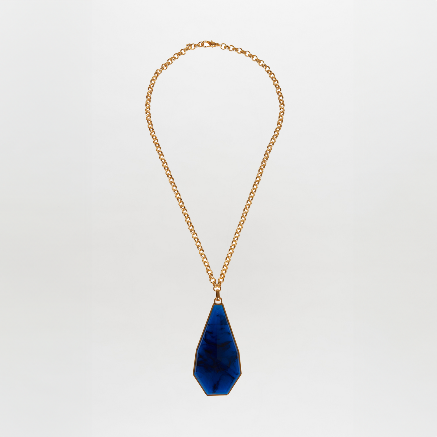 The Ascoli Necklace is a gold chain necklace with a stunning blue geometric tear-shaped Petralux® fantasy stone pendant, crafted from luxurious gold-plated brass.
