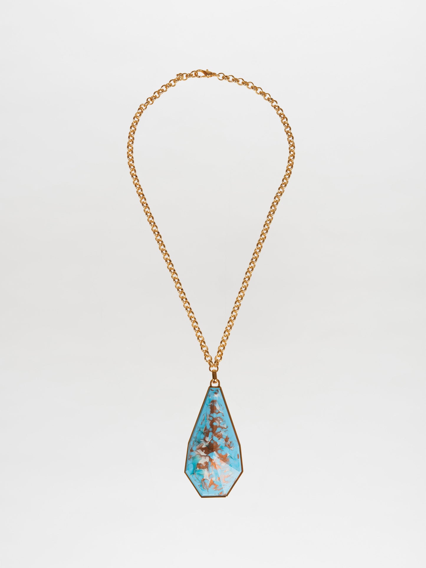 The Ascoli Necklace Aqua features a gold necklace with a large, teardrop-shaped turquoise pendant adorned with a tree-like pattern, masterfully crafted in gold plated brass. This stunning design by Tcherassi beautifully combines elegance and artistry.