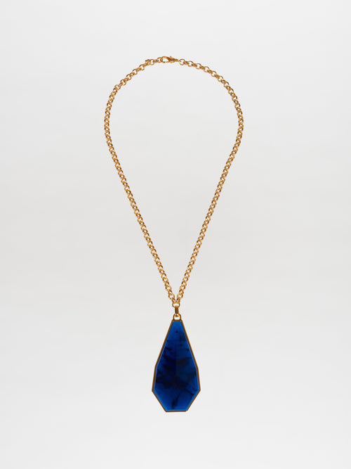 The Ascoli Necklace Navy showcases a gold chain with a large teardrop-shaped pendant made from marbled blue Petralux® fantasy stone, set against a plain white background.