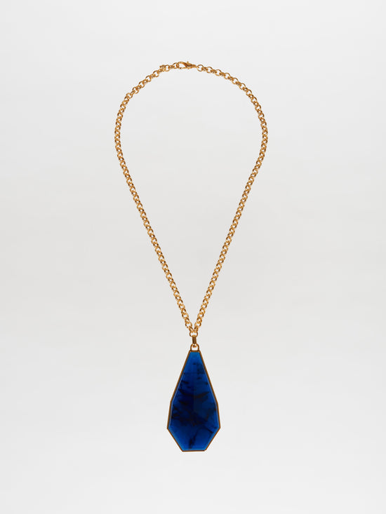 The Ascoli Necklace Navy showcases a gold chain with a large teardrop-shaped pendant made from marbled blue Petralux® fantasy stone, set against a plain white background.