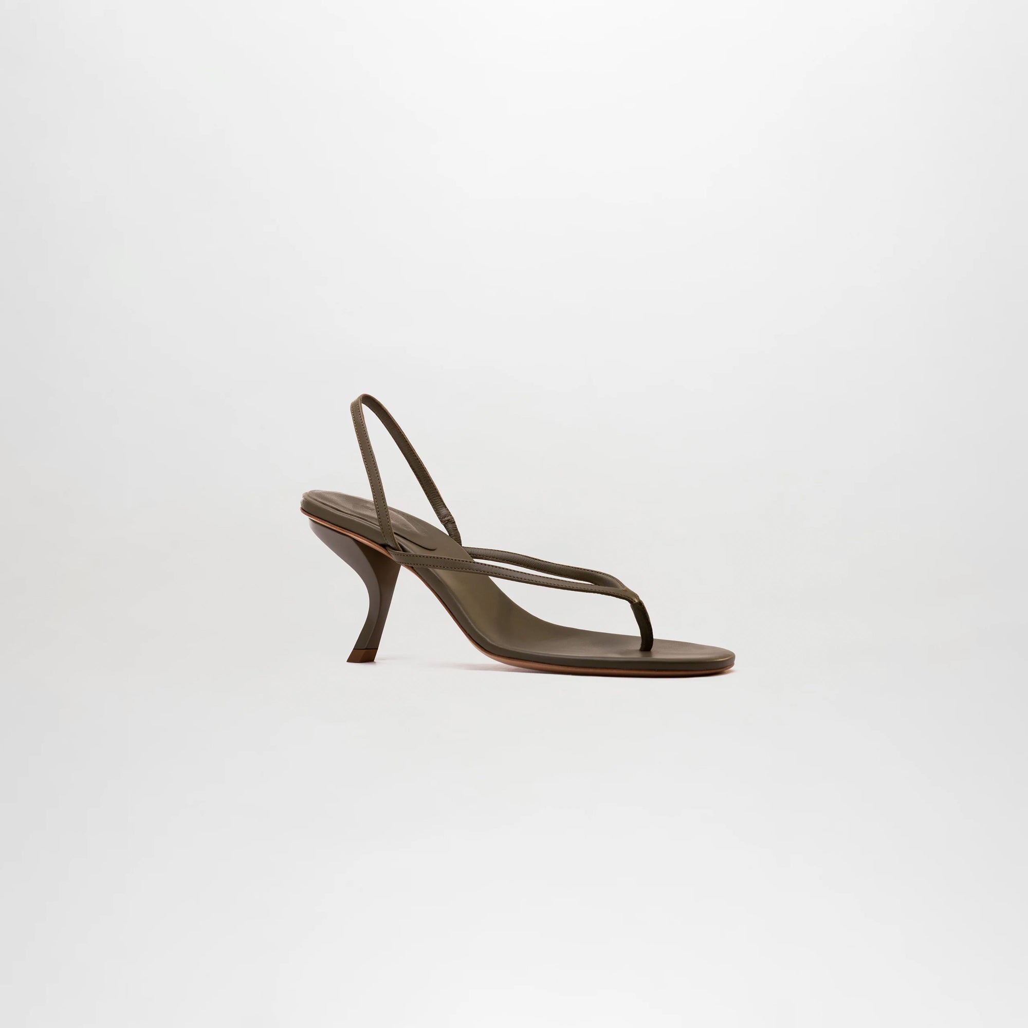 The Aurora Heels are minimalist sandals crafted from dark brown Italian leather, featuring thin straps and a low, curved heel. Shown in profile against a plain light background.