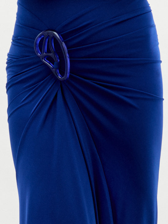 A model wears the Bogna Dress, a sleeveless high-neck blue gown with draped detail, against a plain white background.