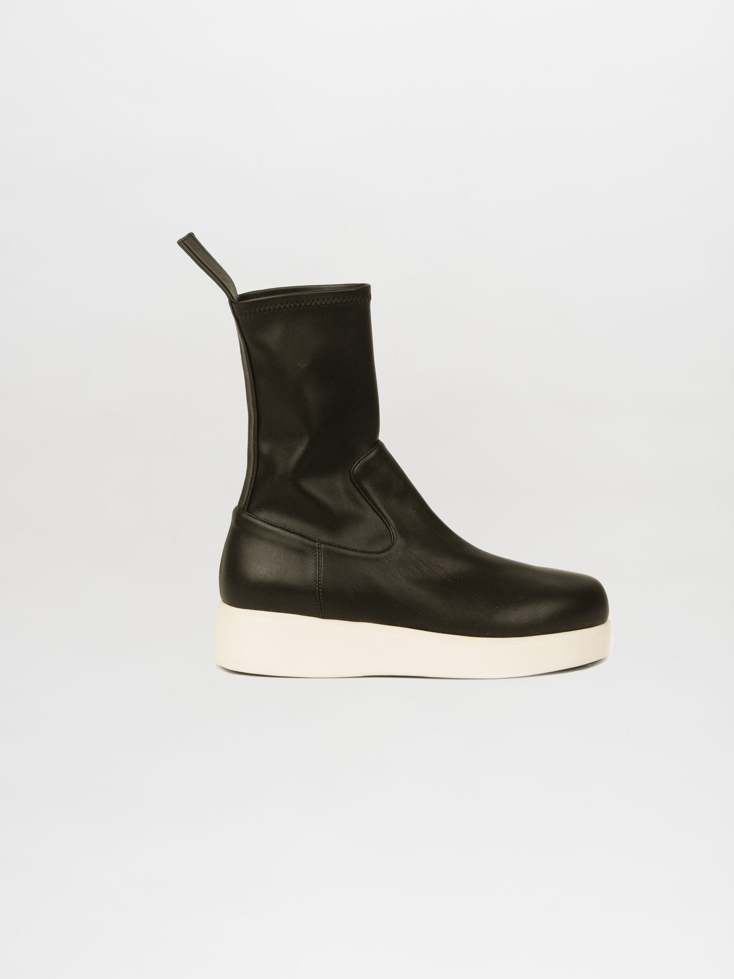 The Baia Boots Black showcase an ankle design crafted from black calf leather, complemented by a striking white platform sole and a handy pull tab on the back, all set against a pristine white background.