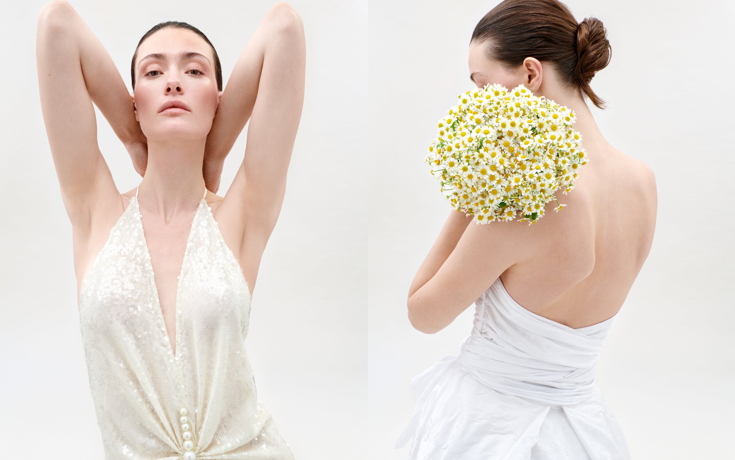 Two women in white dresses, one with arms raised and the other holding flowers, on a plain background.