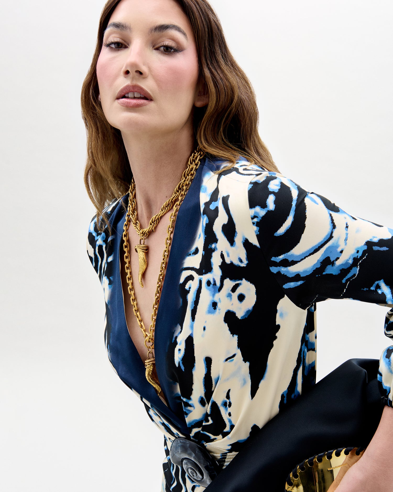 Woman wearing a patterned dress with a gold necklace on a white background