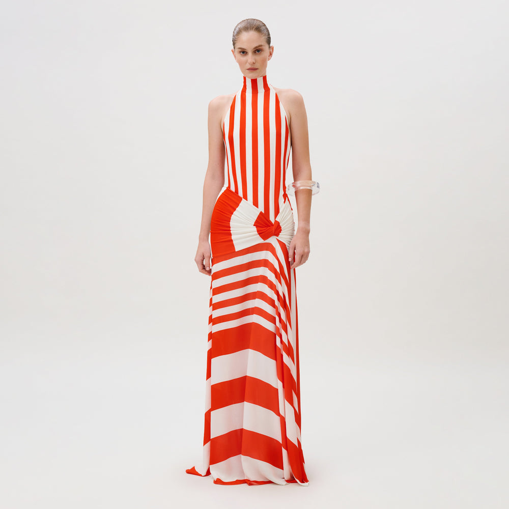 The Belona Dress is a floor-length, high-neck crepe de viscose dress featuring a vertical and horizontal red and white striped pattern with a knotted waist detail.