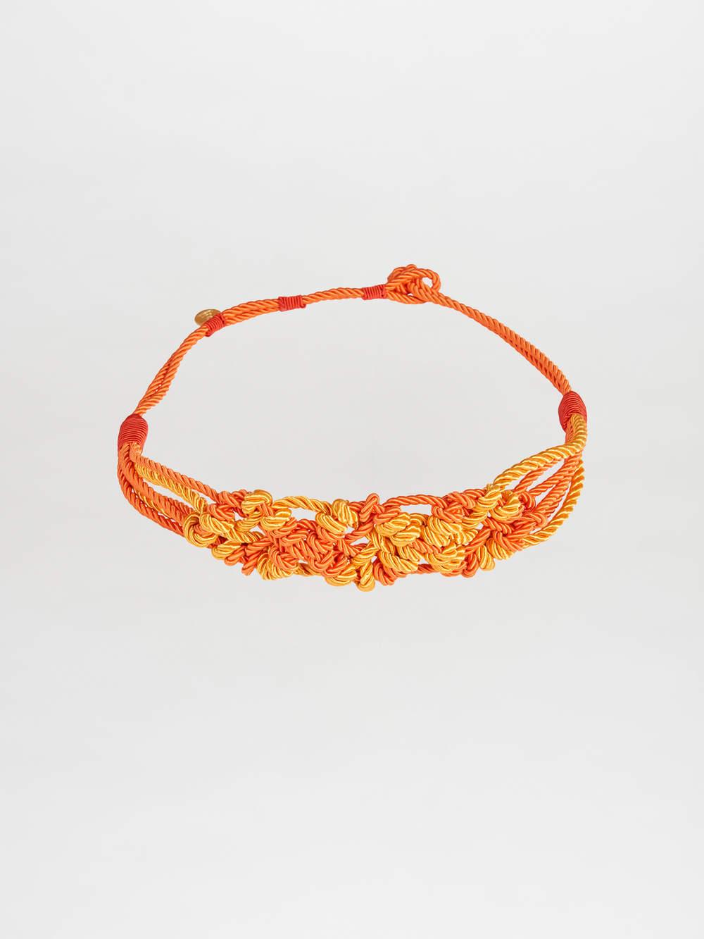 Bresia Belt Orange featuring a nautical knot design and braided orange and yellow rope, reminiscent of days spent aboard a ship, displayed on a plain white background.