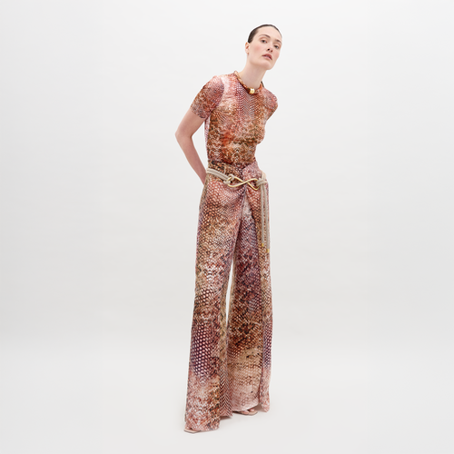 Person wearing a snakeskin-patterned outfit, consisting of a short-sleeve top and high-waisted, wide-leg Canturipe Pant Peach Animal Print, standing against a plain white background. This chic ensemble is available for pre-order and will ship by November 15th, 2024.