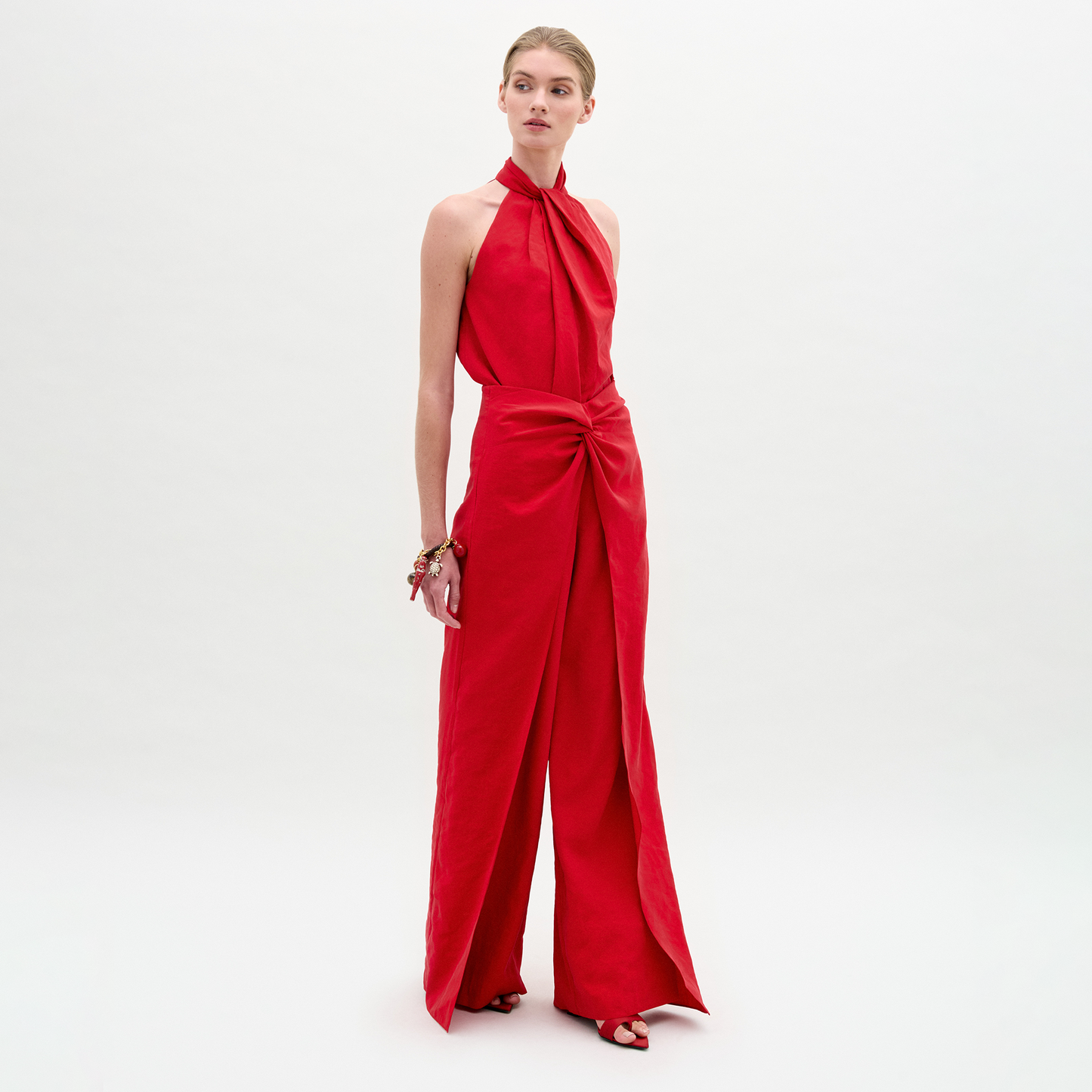 Model showcases the Canturipe Pant, featuring a high-waisted, wide leg silhouette in bold red, styled with a sleeveless halter-neck top against a plain white background.