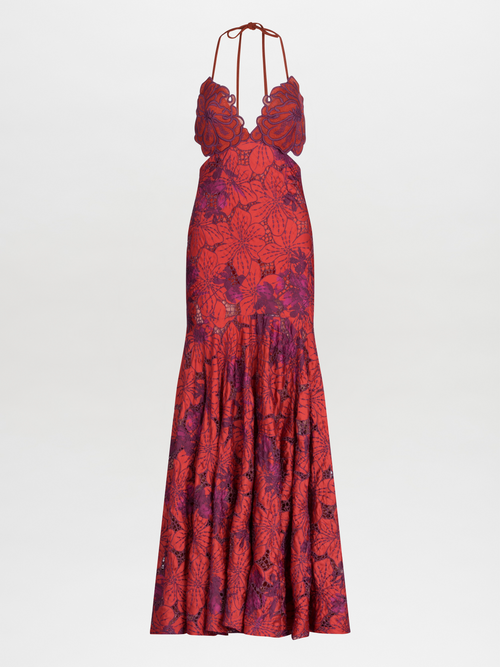 The woman is elegantly dressed in the Cara Dress Red Magenta Embroidery, a floral halter neck maxi dress with an exquisite scalloped guipure lace neckline, standing gracefully against a white background.