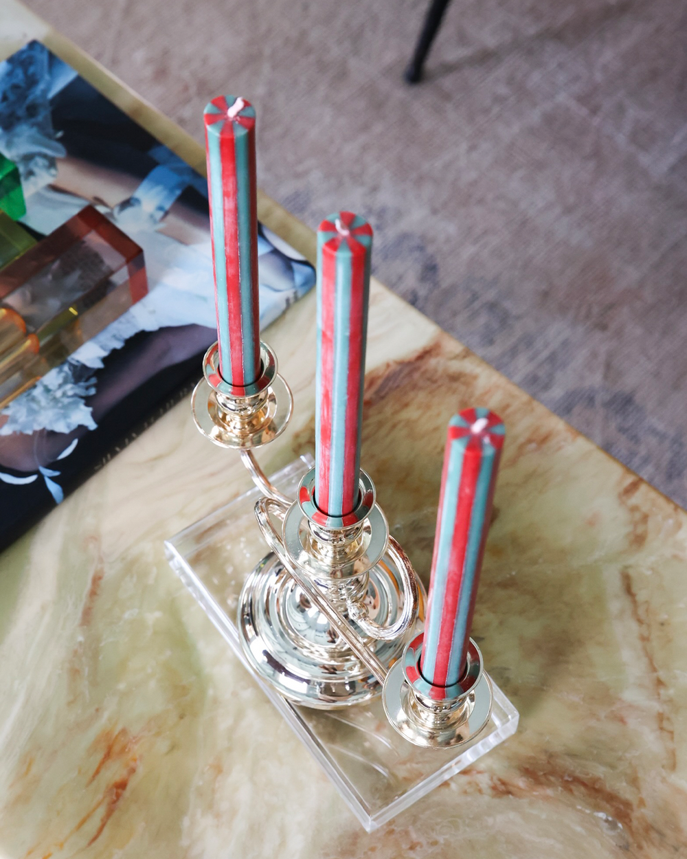 Decorative holder with red and silver candles on a marble surface