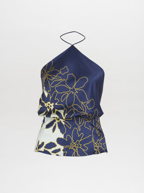 The Chantal Blouse Navy Citrine features a navy blue halter design accented by a yellow floral pattern set against a white backdrop, complete with an elegant open back.