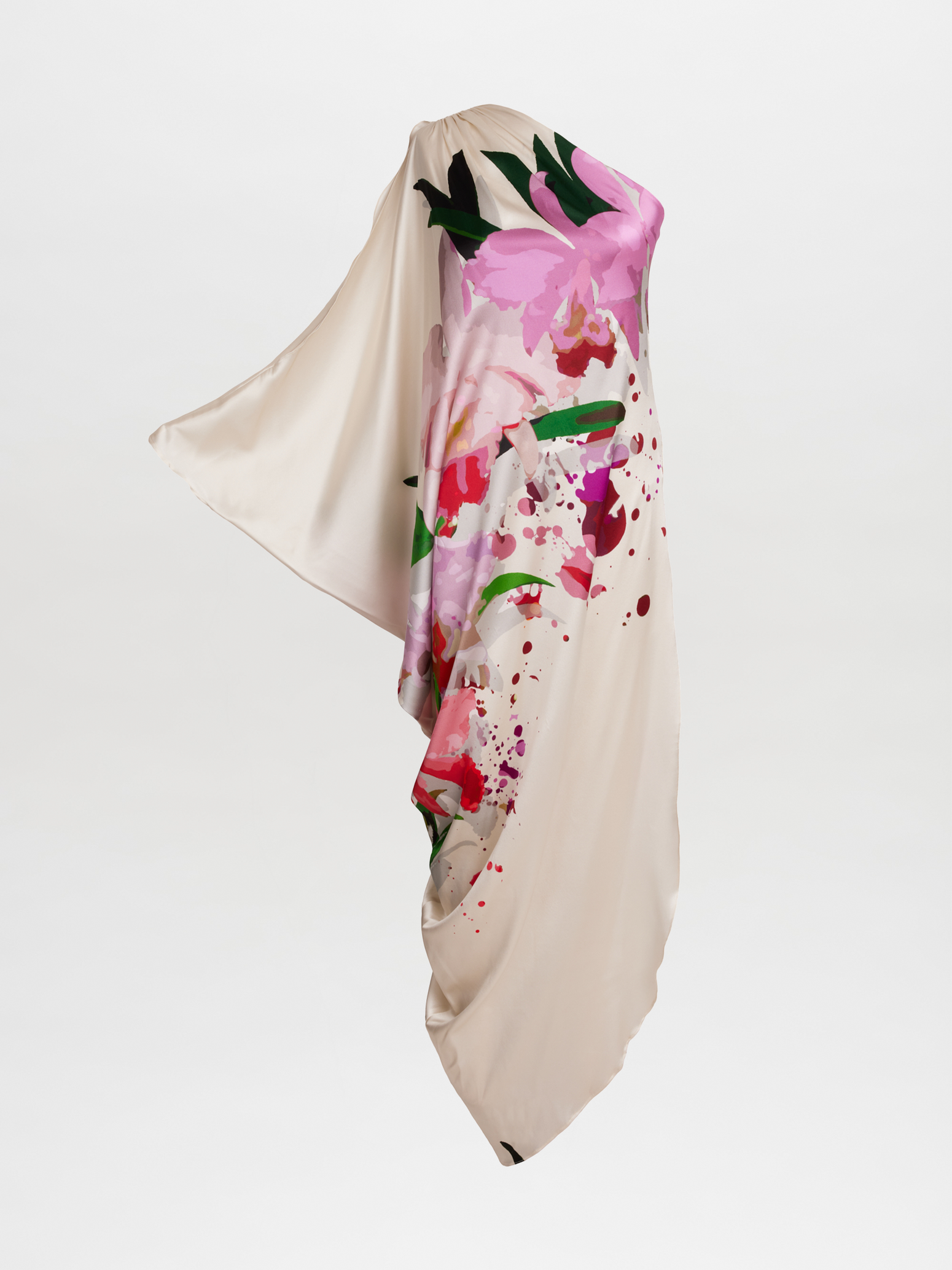 The Chiara Dress, a flowing beige gown adorned with floral designs in shades of pink and green and featuring an asymmetric one-shoulder drape, exudes elegance against a crisp white background.