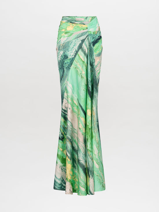 A person wearing the Claudia Skirt Green Marble dress, featuring a long-sleeved design with a shoulder cutout, poses against a plain white background. Pre-order now to ship by February 15th, 2025.