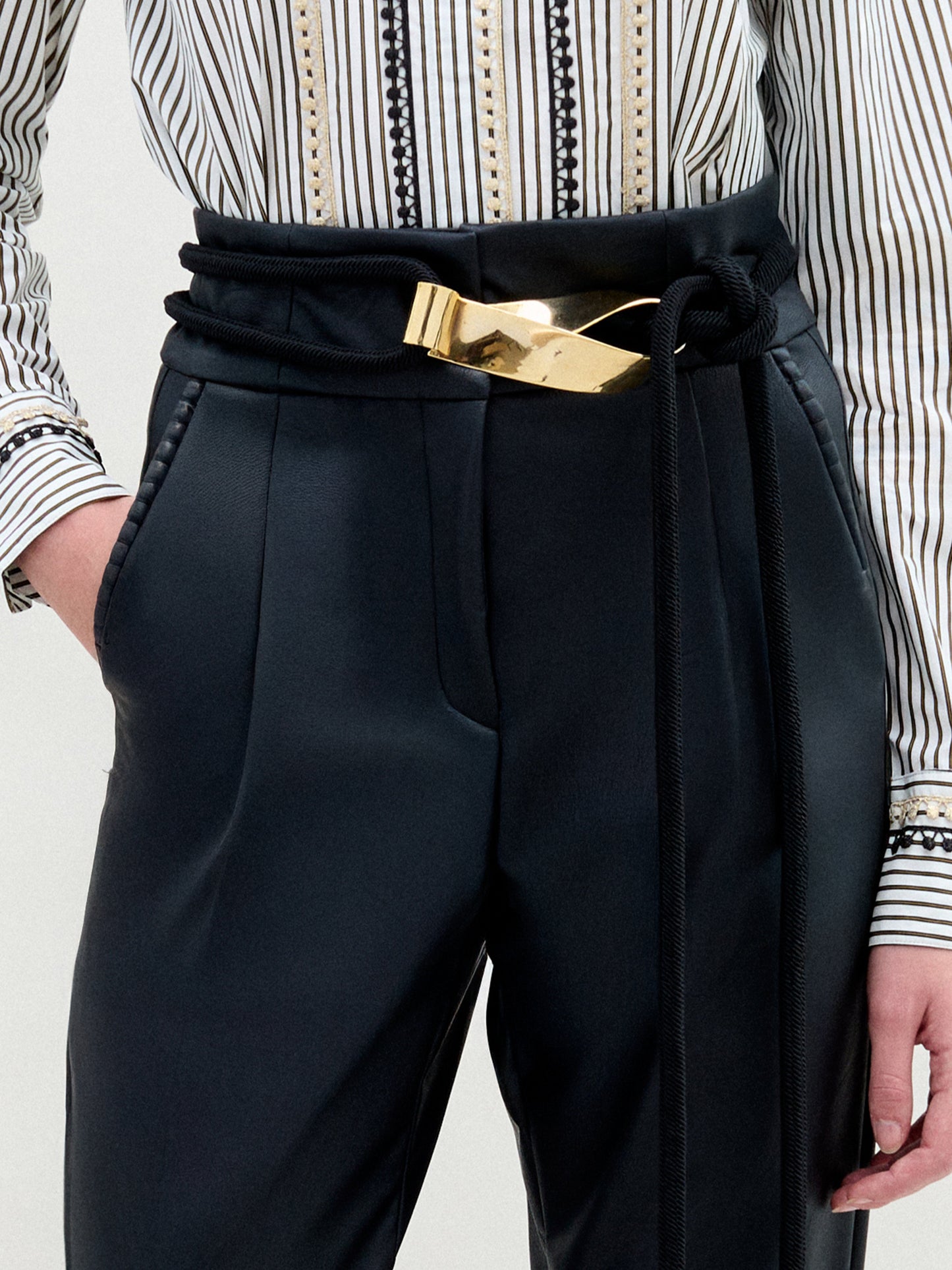 The Daiana Belt is a black cord belt featuring a gold handle and crafted from premium Italian material.
