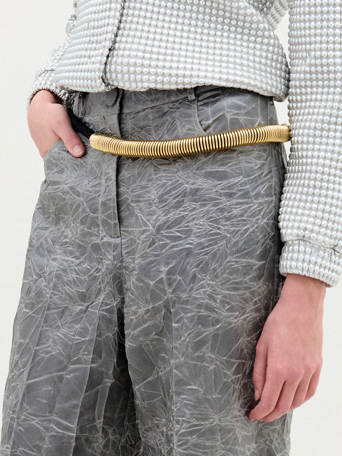 The Dunia Belt, crafted from fine Italian material, features a coiled black cord with gold-capped ends and striking gold accents, artfully arranged in a spiral on a plain white background.