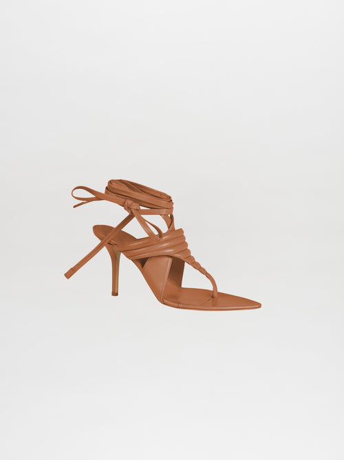 The Dalila Heels Camel showcase a brown strappy high-heeled sandal design, meticulously crafted from Italian calf leather. Featuring a pointed toe and an ankle wrap, they are elegantly set against a plain white background.