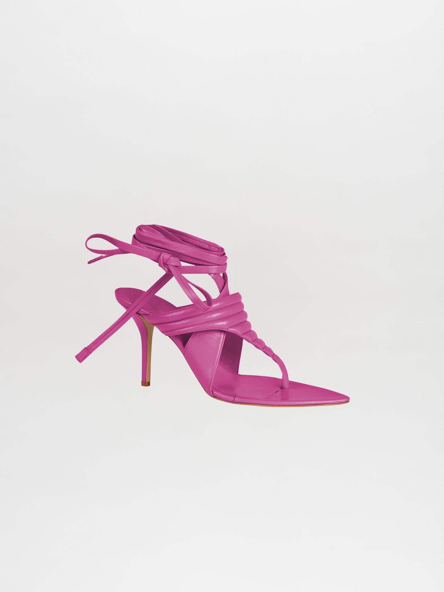 The Dalila Heels Magenta showcases a high-heeled sandal in a vibrant magenta color with a strappy design and ankle wrap, crafted from luxurious Italian calf leather, set against a plain white background.