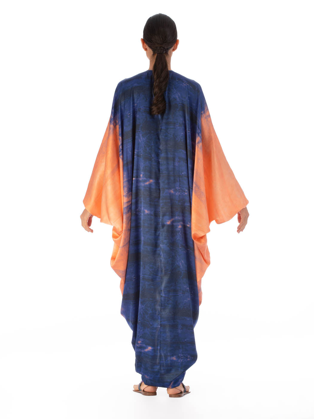 A long, flowing Danette Dress Mediterranean Coral Blue with blue and orange tie-dye patterns, displayed against a white background.